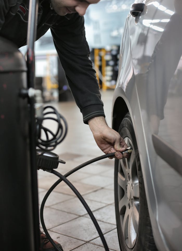 Offerings Mechanic adjusting tire pressure of a vehicle in an indoor automotive service center.