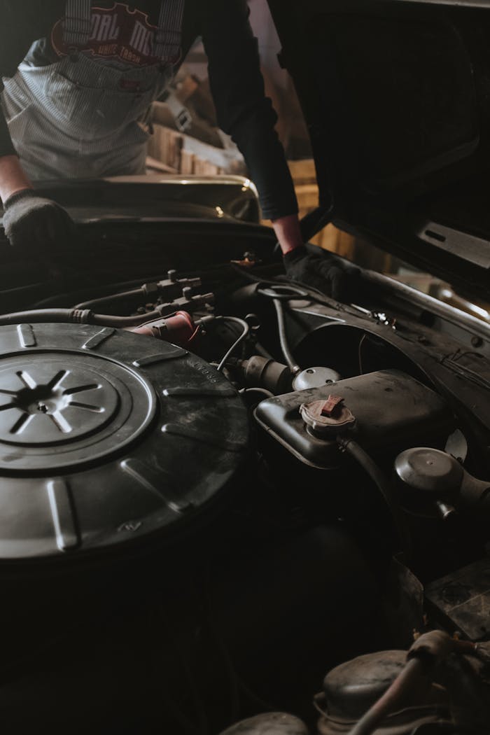 Offerings Close-up of a mechanic repairing a car engine in a garage setting.