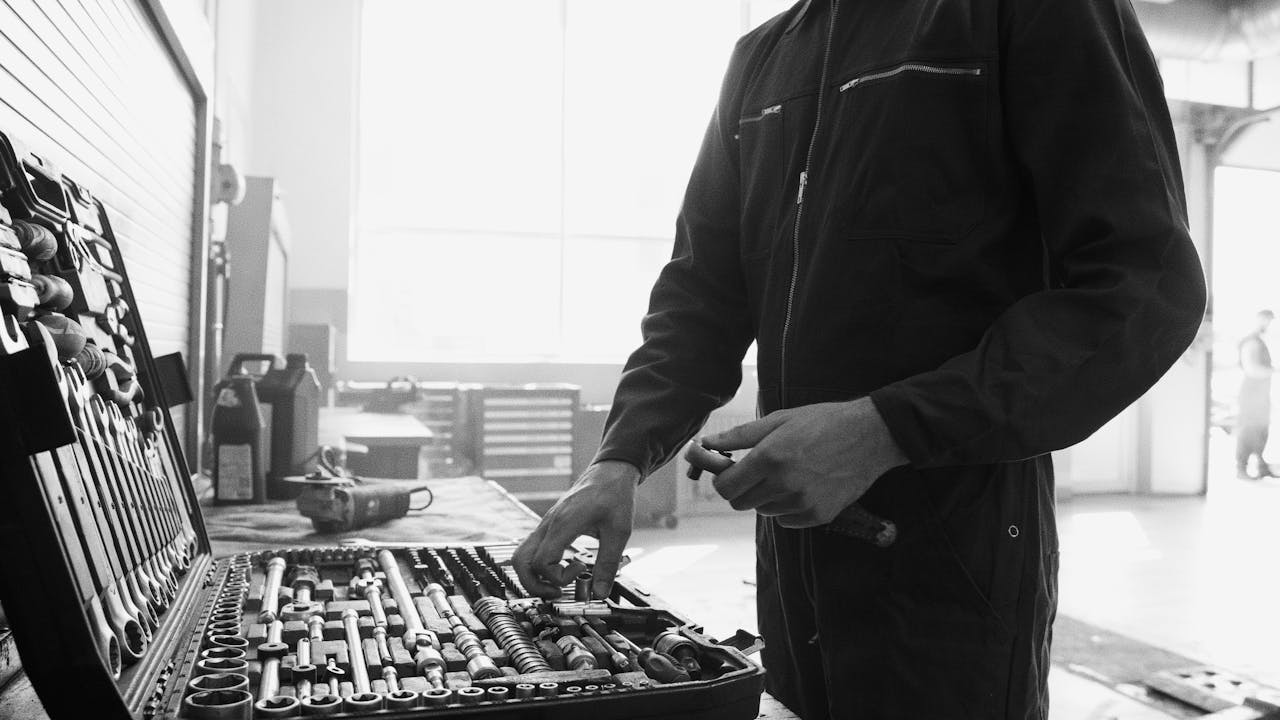 Mechanic in overalls working with a tool set in a garage.