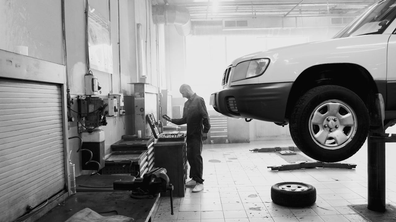 Offerings Black and white image of a mechanic working in an auto repair shop.